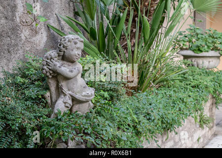 Wand in den Garten mit grünen Pflanzen und eine kleine Skulptur Stockfoto