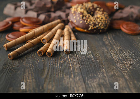 Pralinen Hintergrund. Schokolade. Tasse heiße Schokolade, Zitrone, Muttern und Sortiment an feinen Pralinen in dunkler und Milchschokolade auf dunklen Holztisch Stockfoto