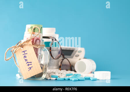 Geld sparen für Krankenversicherung - Geld, Pillen und Flaschen aus Glas Stockfoto