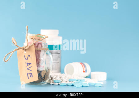 Geld sparen für Krankenversicherung - Geld, Pillen und Flaschen aus Glas Stockfoto