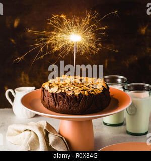 Glutenfreie und vegane Schokolade Mandel paleo Kuchen auf dem Tisch mit brennenden festliche Sparkler Stockfoto