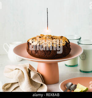 Glutenfreie und vegane Schokolade Mandel paleo Kuchen auf dem Tisch mit brennenden festliche Sparkler Stockfoto
