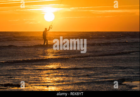 Silhouette von KITESURFER vor der untergehenden Sonne über dem Meer im Herbst in West Sussex, UK. Stockfoto