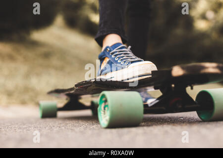 In der Nähe der Beine und Longboard stehen auf Asphalt. Stockfoto
