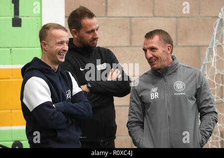 Celtic's Leigh Griffiths (links) und Manager Brendan Rodgers (rechts) mit Street Soccer Gründer und CEO David Duke (Mitte) sehen die Männer und Frauen Street Soccer Teams während einer speziellen Schulung an Lennoxtown, Glasgow. Stockfoto