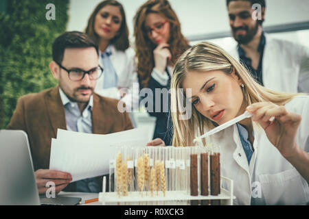 Nahaufnahme einer Universität Biologe die Analyse der Probe der Anlage in das Labor Rohr, Bewässerung mit Tropfen der nahrhaften Flüssigkeit. Stockfoto