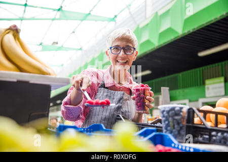 Portrait der älteren Frau verkauft Himbeeren auf dem Markt Stockfoto