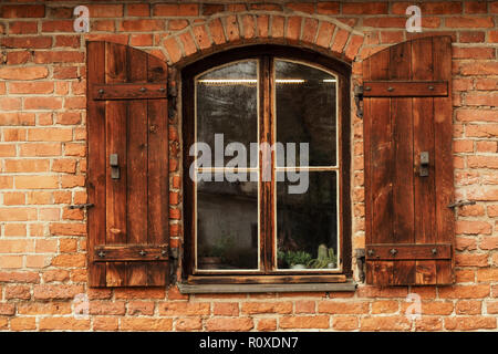 Alte Fenster mit Fensterläden und einer roten Wand Stockfoto