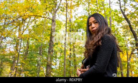 Frau in Schwarz Bluse in Wald im Herbst mit gelben und grünen Bäumen, Stockfoto