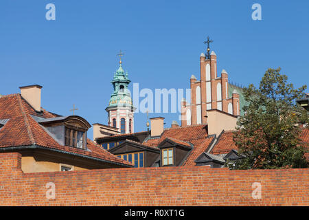Kirchen, die roten Dächer der alten Gebäude hinter Red brick wall in der historischen Altstadt, Warschau, Polen. Stockfoto