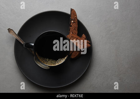 High Angle Shot der Schokolade, Kekse und Kaffee Tasse und Untertasse auf einem Schiefergrau Tabelle. Stockfoto