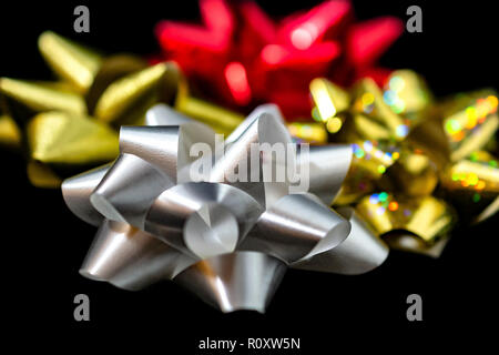 Vier (4) Weihnachten Satinschleife Bänder - Matt Gold Holographic, Rot, Gold & Weiß in der Farbe Schwarz Hintergrund. Zimmer für Kopieren. Stockfoto