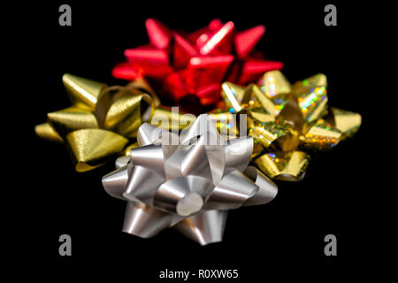 Vier (4) Weihnachten Satinschleife Bänder - Matt Gold Holographic, Rot, Gold & Weiß in der Farbe Schwarz Hintergrund. Zimmer für Kopieren. Stockfoto