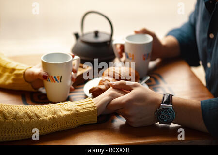 Junges Paar auf Datum halten sich an den Händen und Tassen mit Kaffee. Selektive konzentrieren. Stockfoto