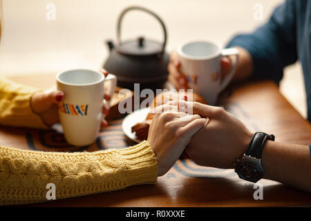 Junges Paar auf Datum halten sich an den Händen und Tassen mit Kaffee. Selektive konzentrieren. Stockfoto