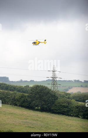 Vertikale geschossen von einem Hubschrauber die Durchführung einer regelmäßigen Inspektion der Freileitungen und Masten in der Britischen Landschaft. Stockfoto