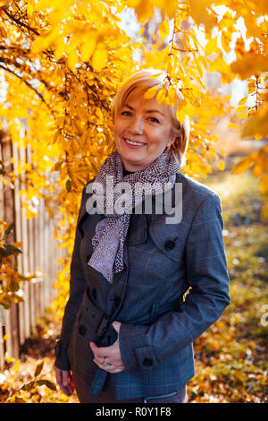 Stilvolle Frau mittleren Alters im Herbst Park posieren. Ältere Dame tragen fallen Kleidung und Zubehör Stockfoto