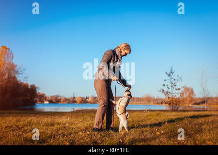 Master walking Mops Hund im Herbst Park am Fluss. Glückliche Frau Fütterung pet. Hund springen Essen zu fangen Stockfoto