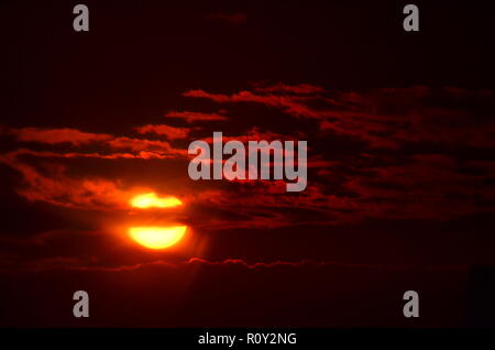 Die Sonne Filterung durch die silhouetting Wolken. Stockfoto