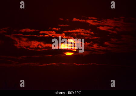 Die Sonne Filterung durch die silhouetting Wolken. Stockfoto