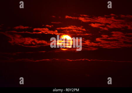 Die Sonne Filterung durch die silhouetting Wolken. Stockfoto