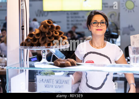 Florenz, Italien - 30 August 2018: Frau, weiblich Verkäufer, Kassierer in Firenze Mercato Centrale, zentrale Markt verkaufen CANNOLI, stehen, lächeln, glücklich Stockfoto