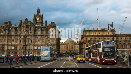 Edinburgh, Schottland, Vereinigtes Königreich, 7. November 2018. UK Wetter: Dunkle Wolken über der Innenstadt Gebäude sammeln. Das Balmoral Hotel Uhrturm auf der North Bridge mit Lothian Buses ist besetzt mit Fußgängern und Baukräne in den neuen St James Entwicklung überragt die Dachlinie Stockfoto