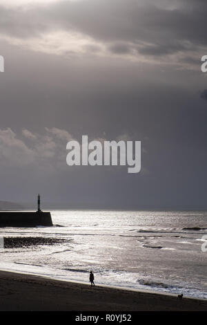 Aberystwyth, Wales, UK. 8. November 2018. UK Wetter: Dunkel brütende stürmischen Himmel über Menschen zu Fuß am Strand entlang in Aberystwyth, da das Wetter wieder versammeln sich nass und windig. Das Met Office haben eine gelbe Warnmeldung für starken Wind, starker Regen und die Wahrscheinlichkeit, dass der Fluss- und Küstengebieten für große Teile von South Wales und dem Westen des Landes morgen Credit: Keith Morris/Alamy Live Neuigkeiten Stockfoto