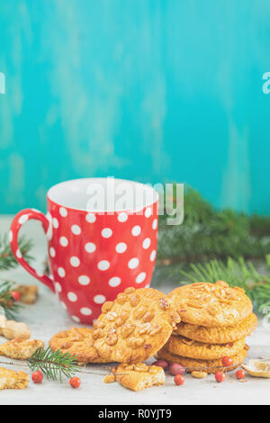 Weihnachten und Neujahr Zusammensetzung mit köstlichen peanut Cookies, Erdnüssen und Tasse Kaffee oder Tee, Niederlassungen Fichte und kiefer Kegel auf Licht Tabelle und Stockfoto
