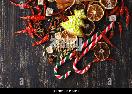 Zutaten für Weihnachten, Winter Plätzchen backen. Lebkuchen, Früchtebrot, saisonale Getränke. getrocknete Orangen, Zimt, Gewürze auf einem schwarzen Tabelle, Ansicht von oben Stockfoto