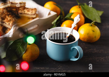 Tasse Tee und Zweig mit Weihnachtsbeleuchtung für den Hintergrund. Stockfoto
