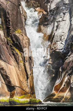 Ein Blick auf den unteren Teil von einem Wasserfall an der Küste von British Columbia, die platzen aus einem schmalen Spalt in einem Granit Felsen (vertikal). Stockfoto