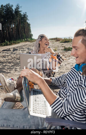 Frau mit Dreadlocks holding Silber laptop Laut lachend Stockfoto