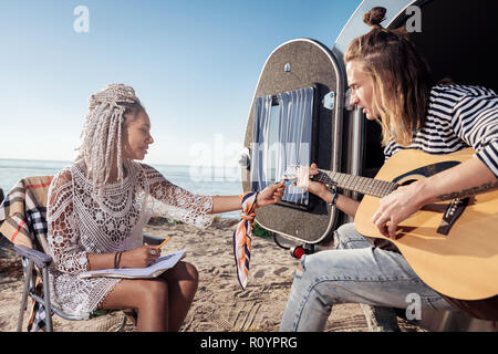 Freundin mit weißen dreadlocks Tuning die Gitarre für Ihren Freund Stockfoto