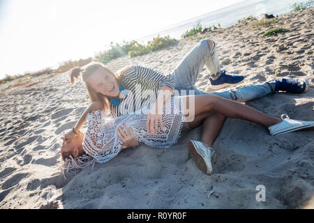 Mann in Jeans und gestreiften Hemd seine Freundin liegen auf Sand umarmen Stockfoto