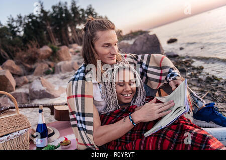 Paar Lesung buchen Sie beim Sonnenuntergang am Strand gemeinsam Stockfoto