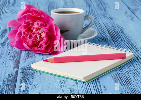 Morgens Kaffee Becher, leer Notebook, Bleistift und weiße Pfingstrose Blumen auf blau Holztisch Stockfoto