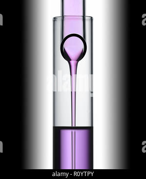 Purple Beauty Behandlung Flüssigkeit gießt aus einem Reagenzglas in einem anderen Studio noch Leben Stockfoto