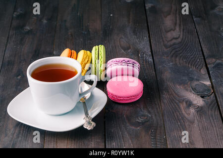 Tasse Kaffee und französischen Macaron an einem alten Holztisch Stockfoto