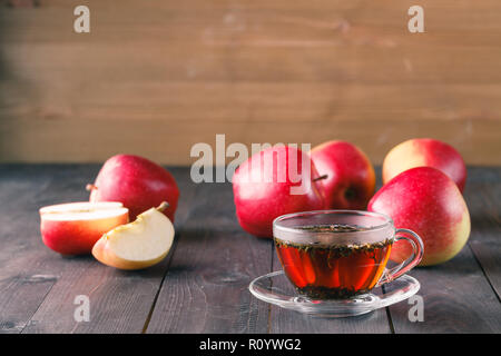 Kräutertee in Glas und Äpfel auf hölzernen Tisch Stockfoto
