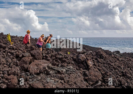 Pahoa, Hawaii - Menschen wandern über die erkaltete Lava 2018 vom Ausbruch des Kilauea Vulkans. Keimen Kokosnüsse sind Platziert eine pathwa zu markieren Stockfoto