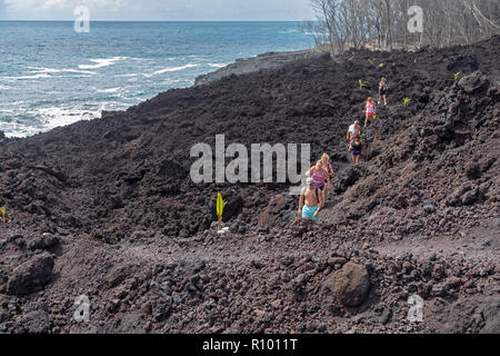 Pahoa, Hawaii - Menschen wandern über die erkaltete Lava 2018 vom Ausbruch des Kilauea Vulkans. Keimen Kokosnüsse sind Platziert eine pathwa zu markieren Stockfoto