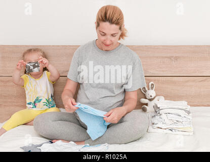 Mutter und Tochter zusammen Kleidung für einen neugeborenen Jungen Stockfoto