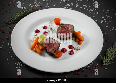 Geschnetzeltes Rindfleisch Braten auf weißen Teller auf dunklem Hintergrund eingerichtet Stockfoto