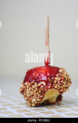 Red Candy Apple in Erdnüssen mit Biss auf einen Vintage Muster Hintergrund. Stockfoto