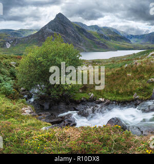 Schöne Panorama Landschaft Bild der Strom fließt über die Felsen in der Nähe von Llyn Ogwen in Snowdonia während eary Herbst mit Tryfan im Hintergrund Stockfoto