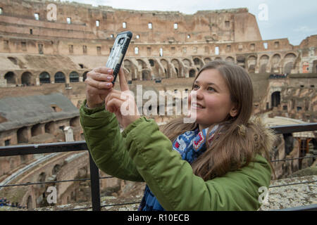 Junge Frau mit Winterkleidung im Kolosseum, Rom, Italien, macht selfie mit Smartphone Stockfoto