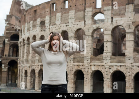 Lächelnde Mädchen tragen weiße Pullover vor dem Kolosseum, Rom, Italien, und fragen sich, schaut entsetzt Stockfoto