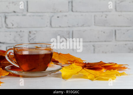 Blätter im Herbst, warme dampfende Tasse Tee auf Holz- Hintergrund Stockfoto
