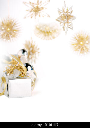 Kleines Weihnachtsgeschenk geschmückt mit Kugeln, Gold Snowflake Dekorationen im weißen Hintergrund hängenden Stockfoto